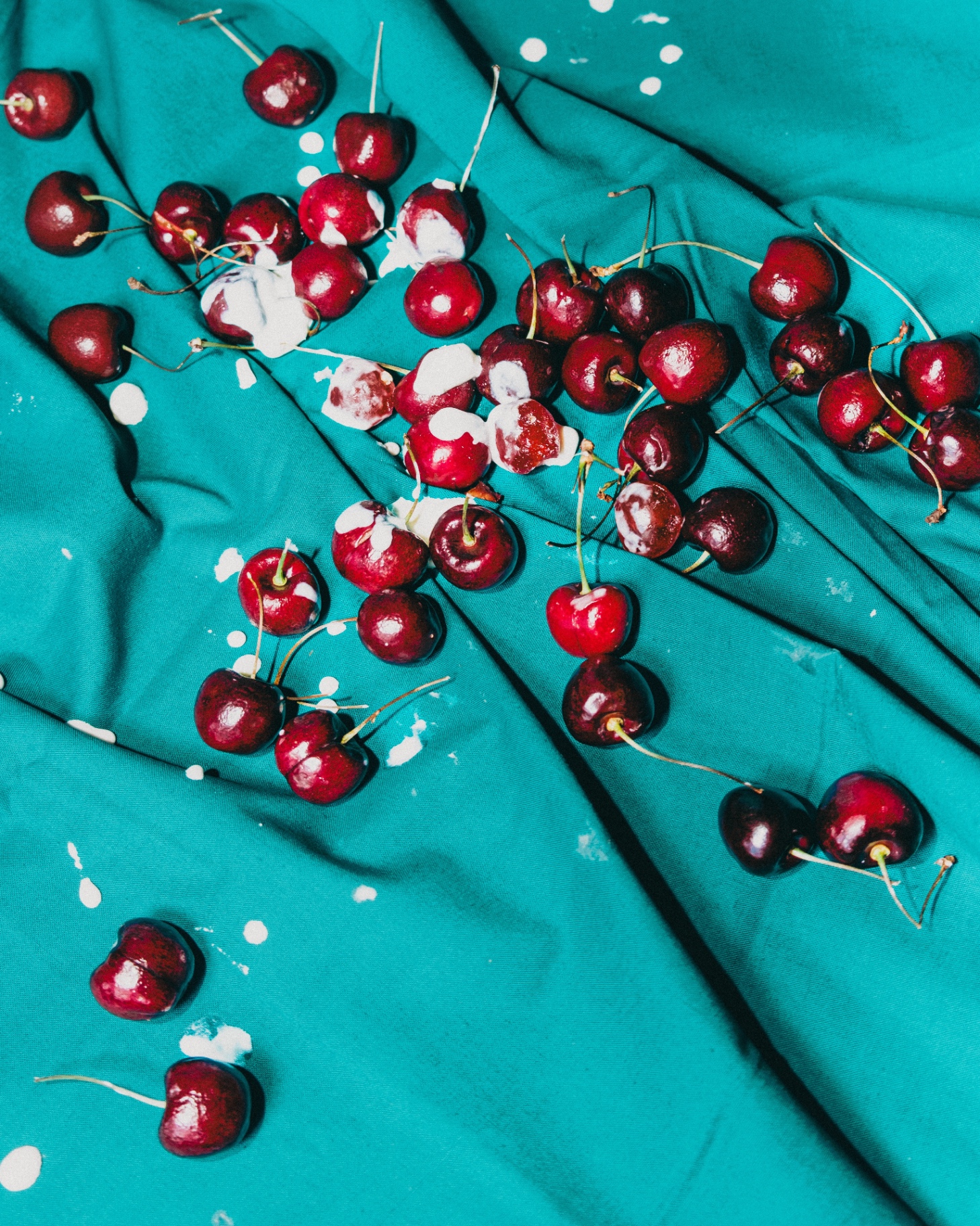 Cherries scattered on bright teal fabric